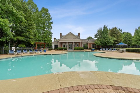A large swimming pool with a house in the background.