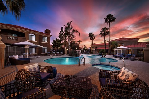 a swimming pool at sunset at a resort with chairs and umbrellas