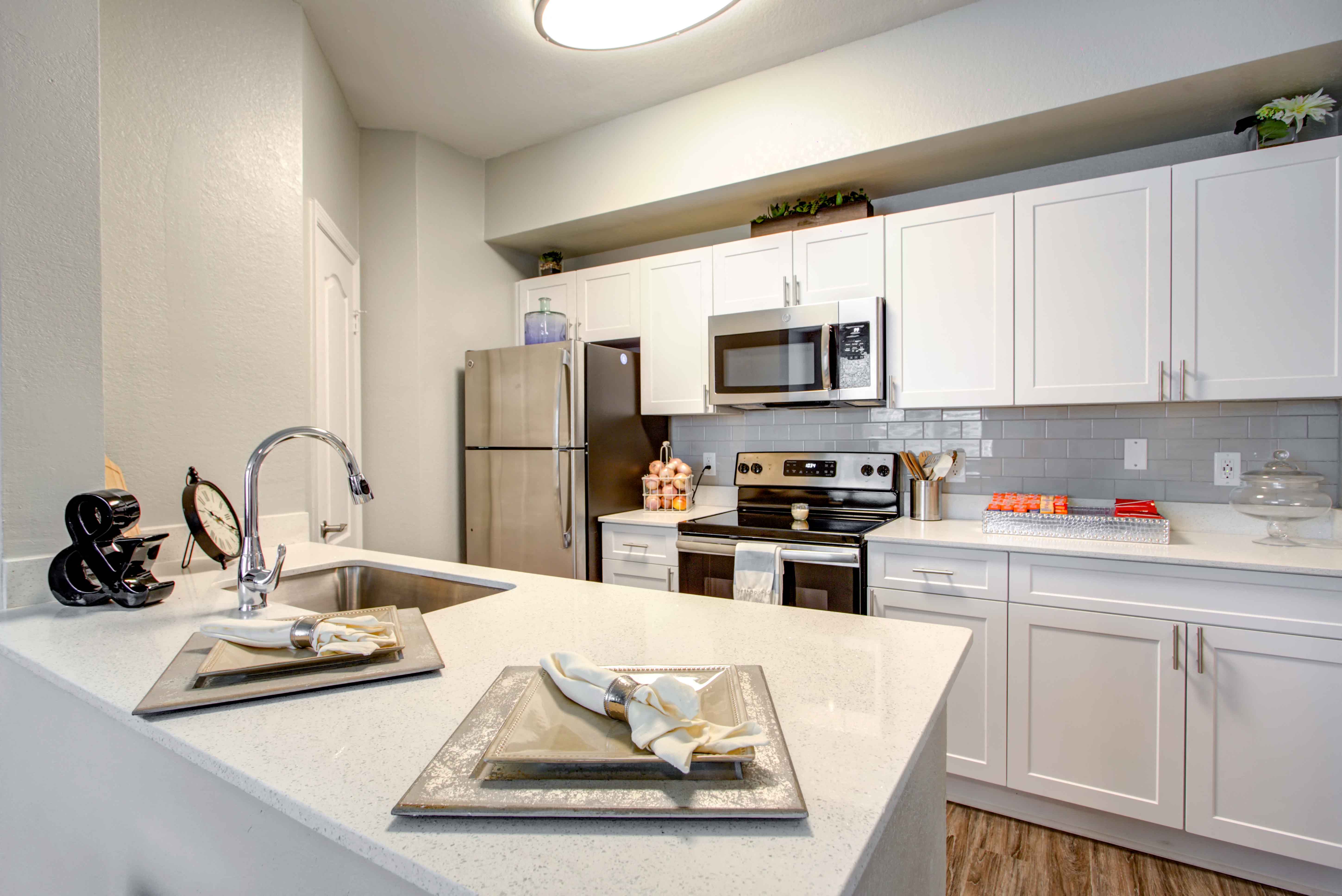 A kitchen with white cabinets and a marble countertop.