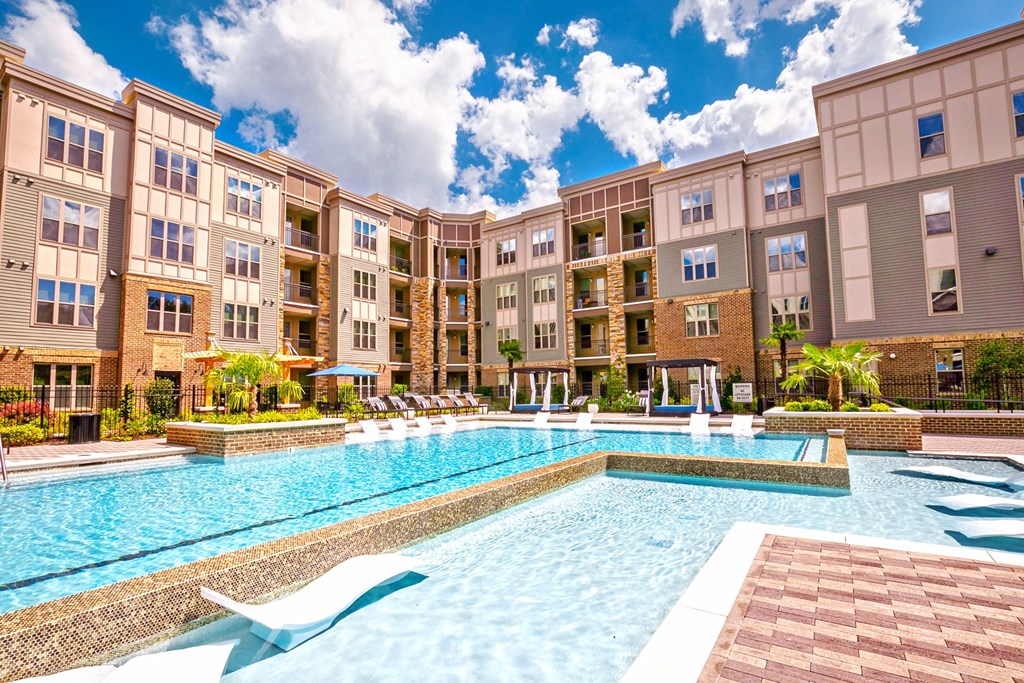 a swimming pool with lounge chairs and umbrellas in front of an apartment building at Artesia Big Creek, Alpharetta, GA, 30005