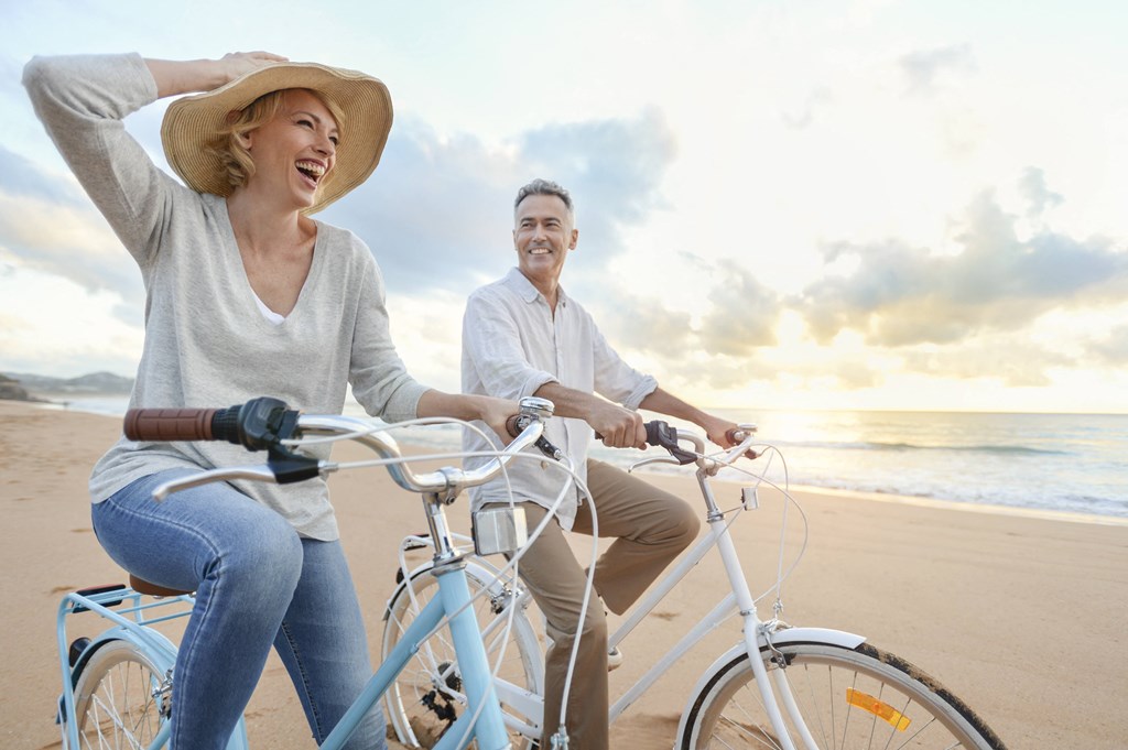 a man and woman riding bikes on the beach