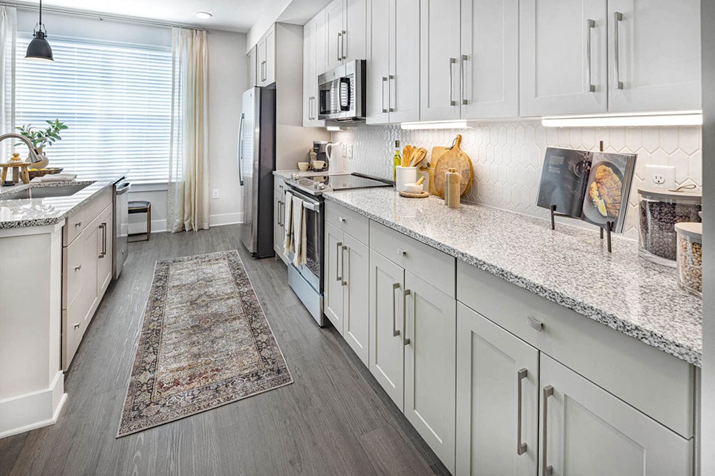 A kitchen with white cabinets and a rug on the floor.