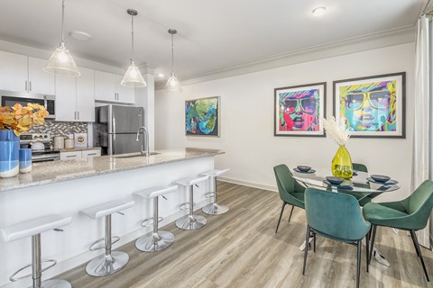 a dining room and kitchen area with a bar and a table and chairs
