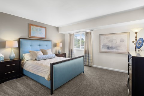 A bedroom with a blue bed and a painting on the wall.