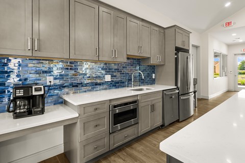 A kitchen with a white counter top and a blue tile backsplash.