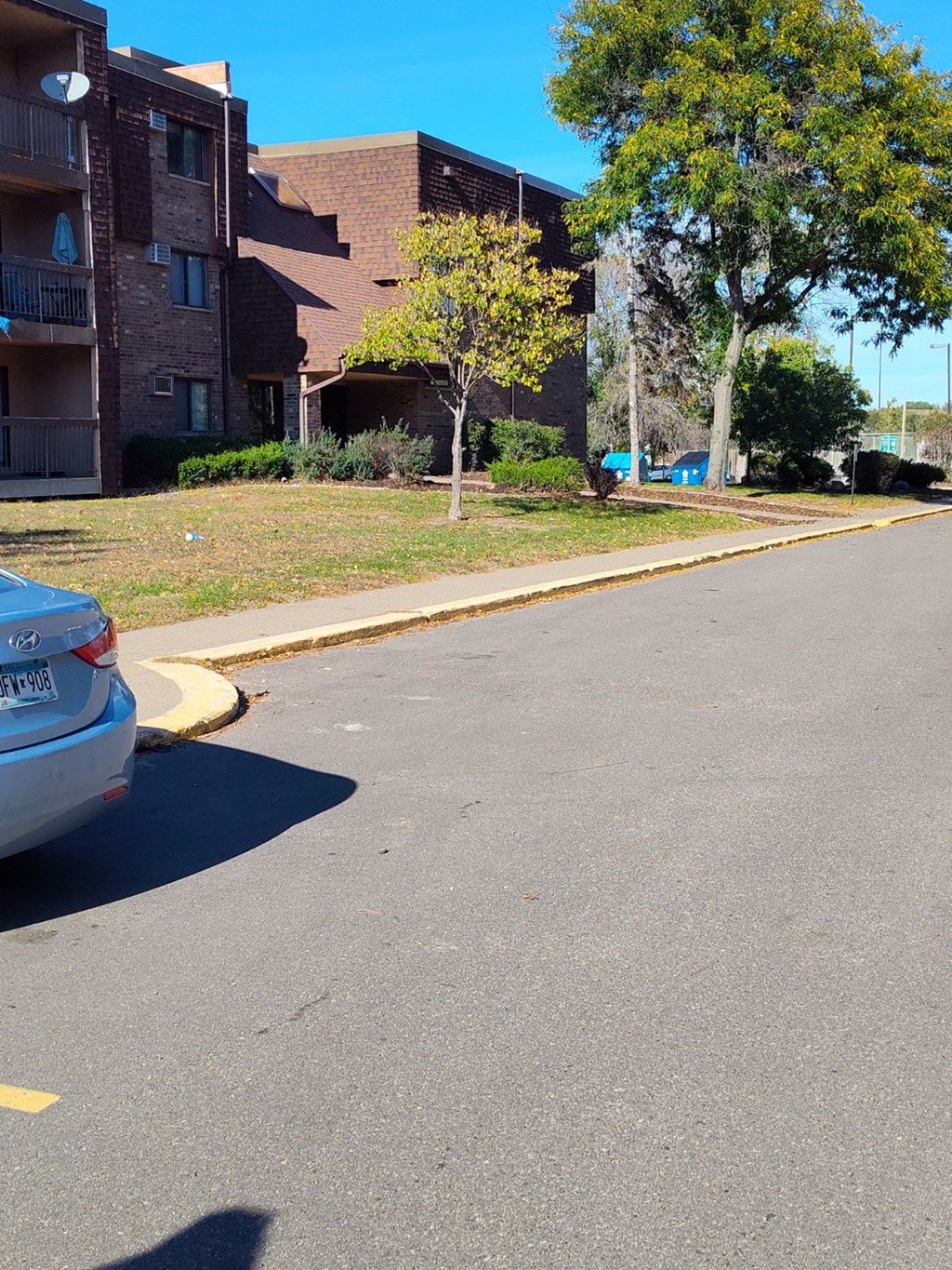 a street with a car parked in front of an apartment building
