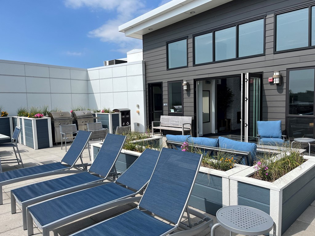 a group of blue lounge chairs and tables outside of a building