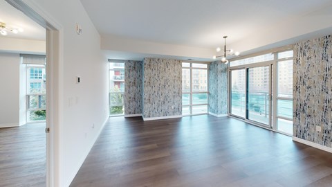 A spacious room with wooden floors and large windows.