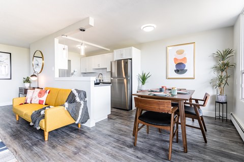 a living room and dining room with a table and a refrigerator