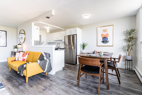 a living room and dining room with a table and a refrigerator