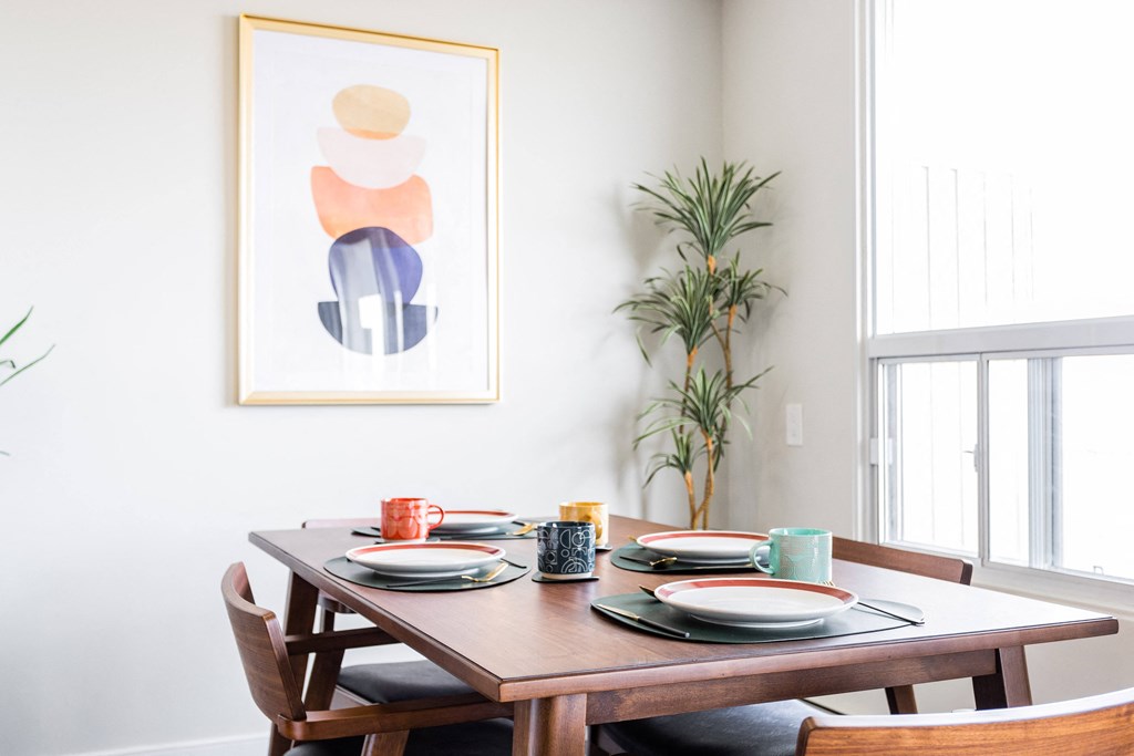 a dining room with a wooden table and a print on the wall