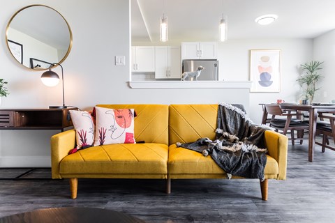 a living room with a yellow couch with pillows and a blanket