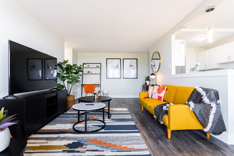 A living room with a yellow couch and a black television.