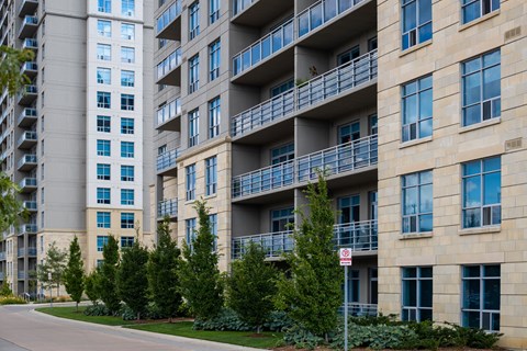an apartment building with balconies and trees in front of a street