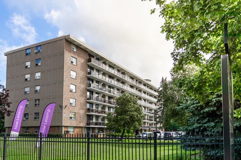 A tall building with balconies and flags in front of it.