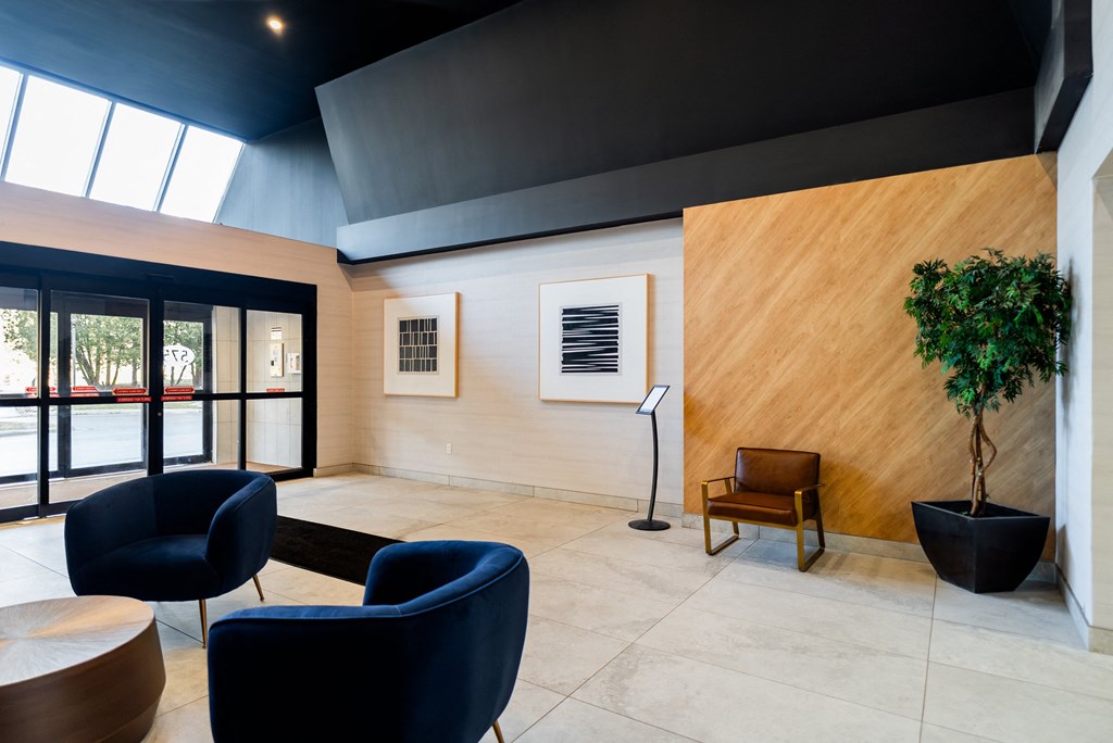 a lobby with blue chairs and a wooden wall and glass doors