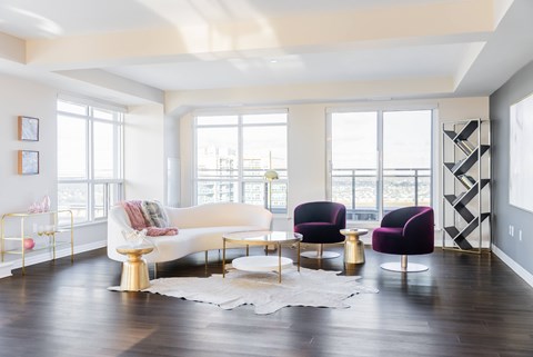 A white sofa with a gold base sits in a room with purple chairs and a white rug.