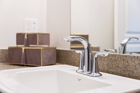 A modern bathroom with a white sink and a silver faucet.