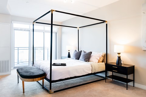 A bedroom with a four poster bed and a bench.