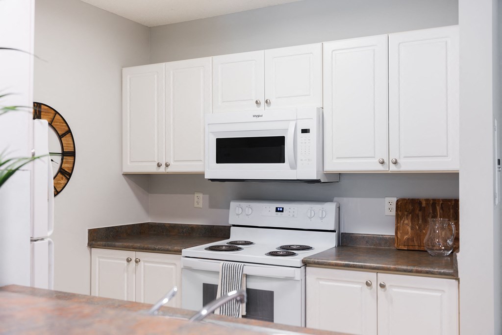 a kitchen with white cabinets and a white stove and microwave