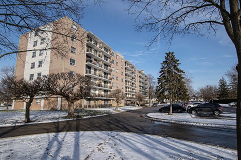 an apartment building on a snowy street with cars parked next to it