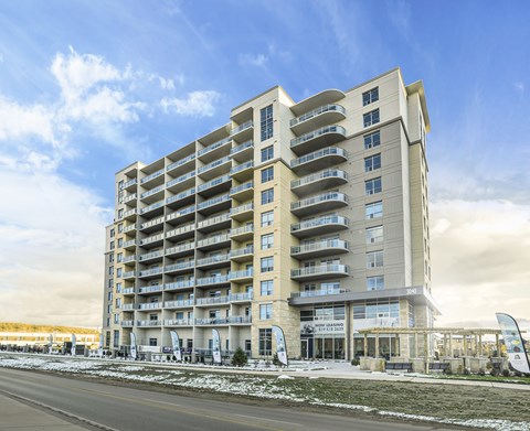 A large, modern apartment building with many balconies and a clear sky above.