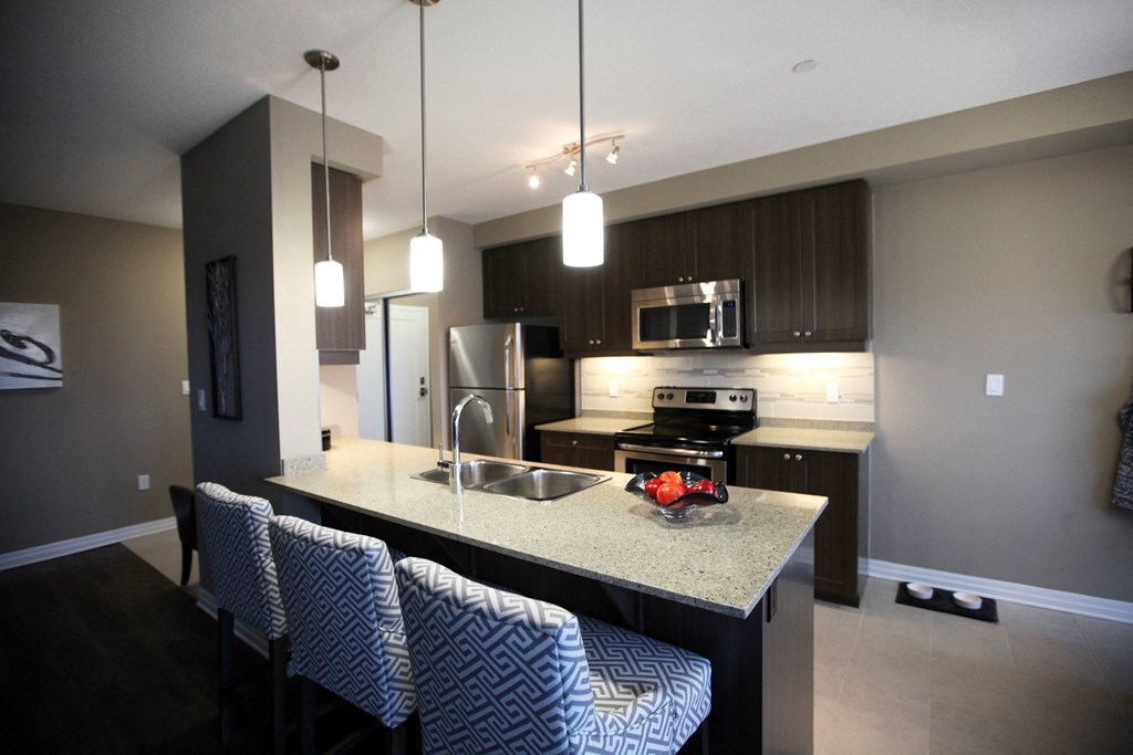 a kitchen with a island with four stools and a stainless steel refrigerator