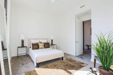 A bedroom with a large bed and a potted plant.