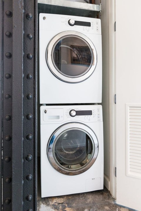 Two white front loading washing machines stacked on top of each other.
