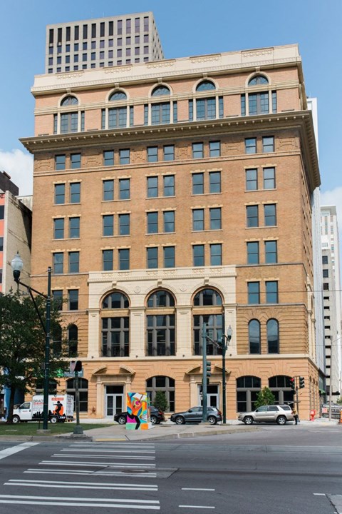 A large, old building with many windows sits on a city street corner.