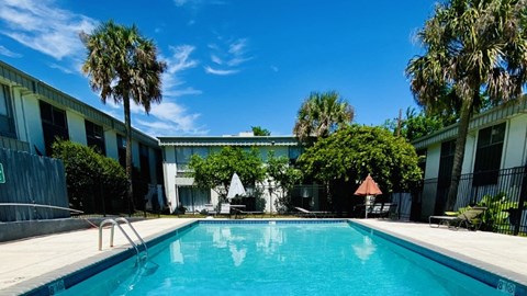 A swimming pool surrounded by palm trees and buildings.