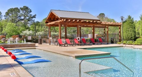 a swimming pool with a pavilion and chairs around it