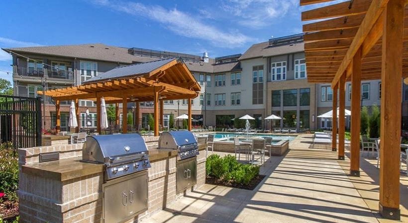 an outdoor area with barbecue pits and a building with a pool