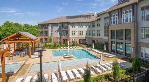 an outdoor pool with chairs and umbrellas at an apartment building