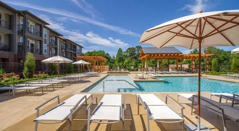 a pool with chairs and umbrellas next to a building