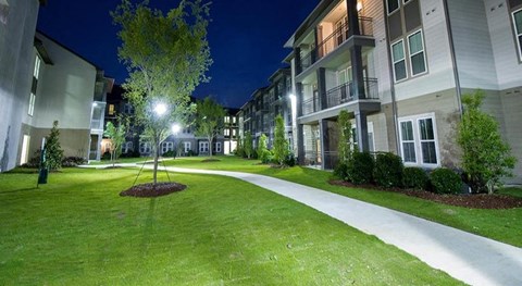 a walkway in the middle of an apartment complex at night