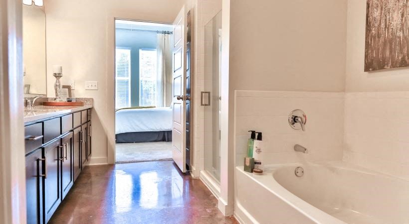 a bathroom with a tub and a sink and a bedroom
