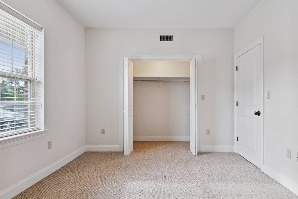 a bedroom with white walls and carpet