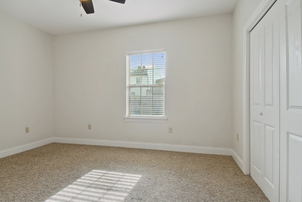 a bedroom with a ceiling fan and a closet