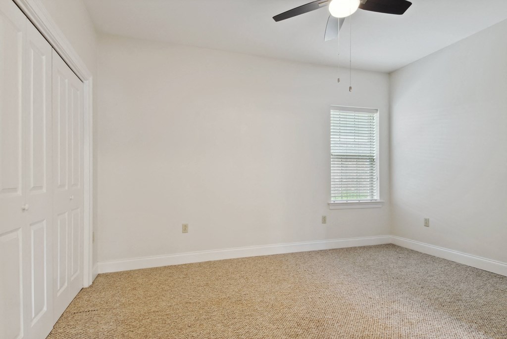 a bedroom with white walls and a ceiling fan