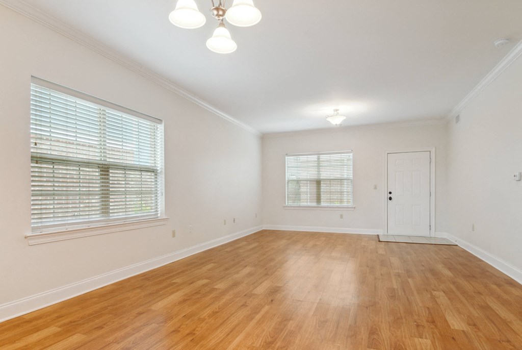 a bedroom with hardwood floors and two windows