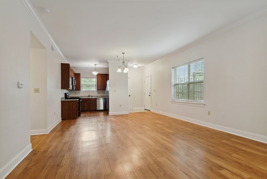 a living room with hardwood floors and a kitchen in the background