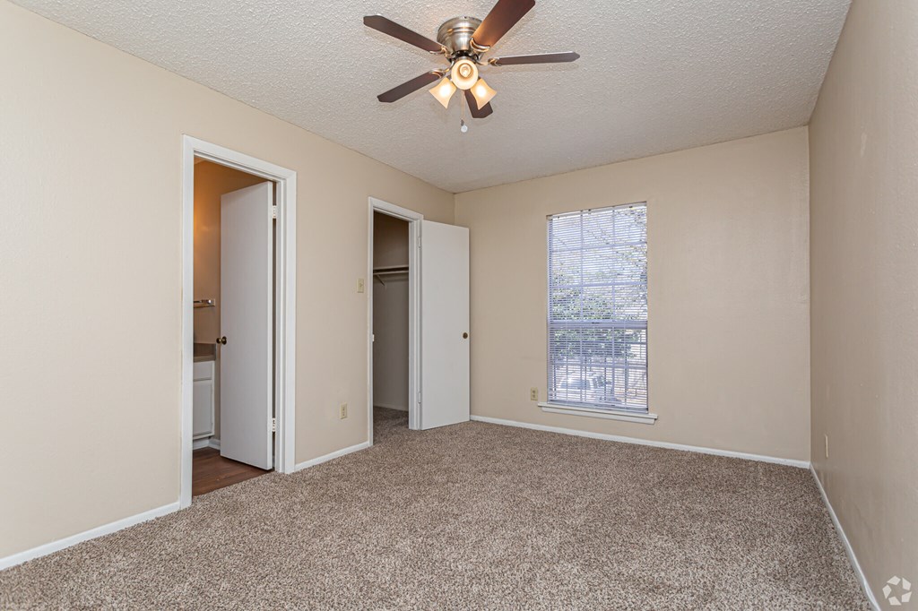 A room with a ceiling fan and carpeted floor.