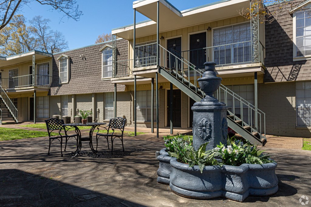 A courtyard with a fountain and benches in front of apartment buildings.