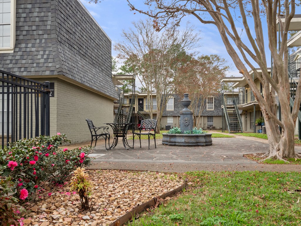 A courtyard with a fountain, benches, and trees.