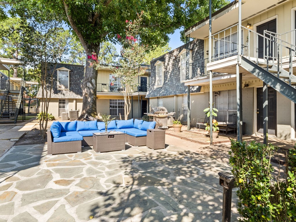 A patio with a stone floor and a blue couch.