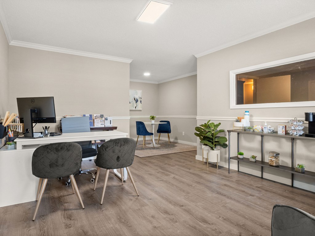 A room with a desk, chairs, and a mirror.