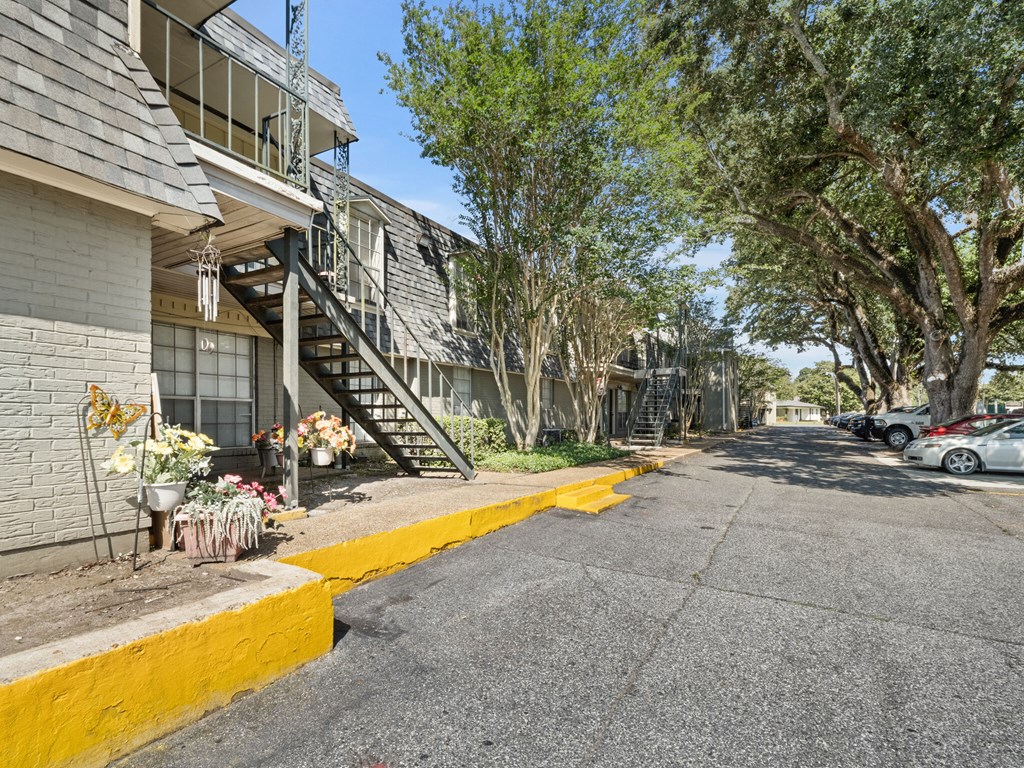A street view with a yellow curb and a building with a staircase.