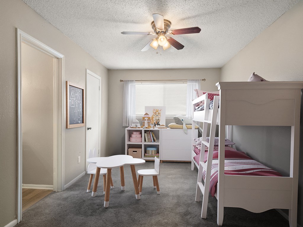 A room with a bunk bed, a table and chairs, and a window with curtains.