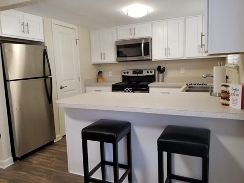 A kitchen with white cabinets and a stainless steel refrigerator.